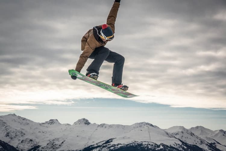 A snowboarder jumping against a mountain range